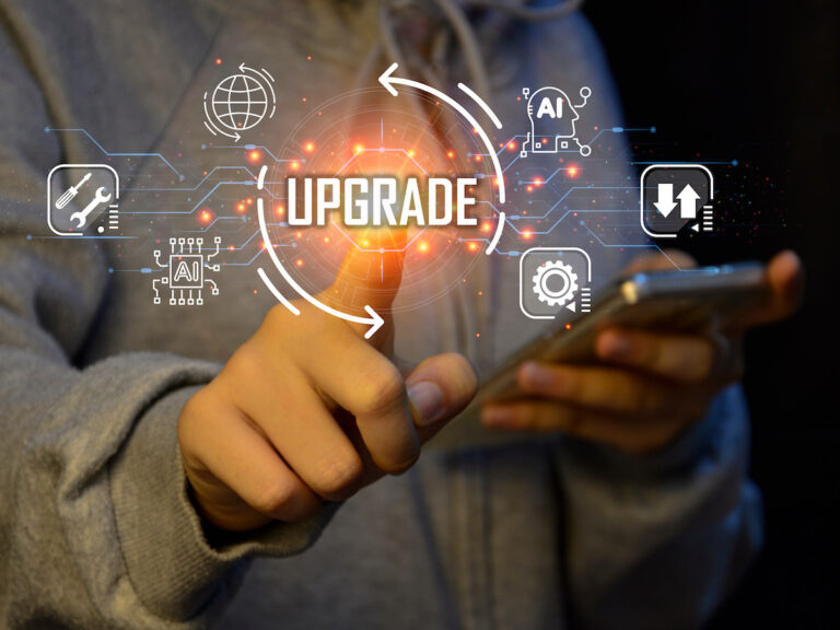 Person using a smartphone with a digital overlay showing the word 'UPGRADE' surrounded by technology icons.